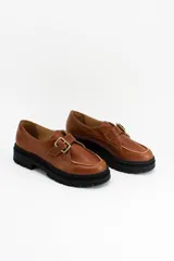 Mocasines de cuero color suela con detalle de hebilla metálica lateral y suela track negra de goma.