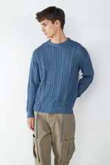 Sweater de punto color azul, con cuello redondo, manga larga y diseño de tejido a cables. Presenta detalles de cordones decorativos en el ruedo.