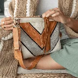 Bandolera color tostado, plata y blanco, confeccionada en cuero. Tiene una manija corta y una correa larga ajustable y removible. Su interior se encuentra forrado de tela gruesa.