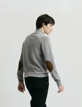 Sweater de punto azul con medio cierre frontal, cuello alto y detalles en símil nappa en la cartera del cierre y coderas.