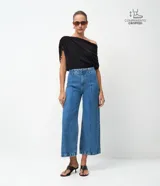 Pantalón de jean modelo wide leg cropped con cintura alta y sastre. Presenta costuras verticales frontales, bolsillos laterales y cierre delantero tradicional.