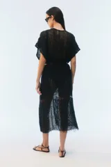 Kimono largo de algodón negro con punto calado, calce amplio, hombros caídos, mangas cortas, aberturas laterales y terminación desflecada en el ruedo.