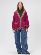 Cardigan de tejido de punto con diseño de ochos, corte oversize y mangas largas con puños acanalados. Presenta un escote en V con solapas en contraste, cierre frontal con botones y dos bolsillos delanteros con bordes en contraste. El diseño incluye detalles de rayas en los puños y en el ruedo.