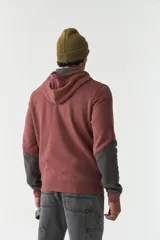 Campera de felpa de diseño color block en tonos marrón y negro, con capucha con cordón ajustable, cierre frontal y bolsillos. Presenta lettering estampado en el pecho.