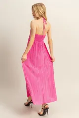 Vestido largo de corte fluido con diseño plisado en toda la prenda. Presenta escote halter con detalle de nudo en el centro del pecho y espalda descubierta.