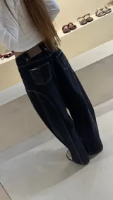 Pantalón de jean tipo balloon de tiro bajo, color marrón oscuro. Presenta un diseño con recortes curvos en las piernas, cierre frontal con doble botón en la cintura y costuras reforzadas.