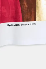 Camiseta de algodón color marrón oscuro, de corte regular, cuello redondo y manga corta. Presenta una estampación metalizada dorada en el parte frontal con texto "REYKJAVIK ART GALLERY" y "ABSTRACT MOVEMENTS Reykjavik, Iceland, 1975".