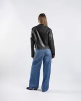Campera de cuero sintético negro estilo motero con cuello mao, cierre frontal, bolsillos con cierre y detalles de tachas en hombros y mangas.