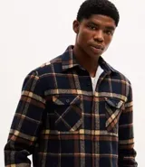 Campera tipo trucker de franela con estampado de cuadros, cuello inglés, cierre frontal con botones, bolsillos con solapa en el pecho y bolsillos laterales. Cuenta con forro interno de sherpa para mayor calidez.