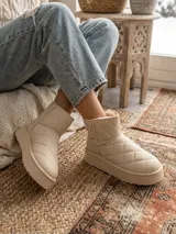Bota corta tipo pantubota color beige, con diseño acolchado de costuras en rombos, interior forrado en piel sintética y suela de plataforma plana.