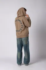 Buzo canguro oversize de frisa de algodón premium en color azul grisáceo. Presenta un diseño con recortes frontales, bolsillo tipo canguro y un pequeño logo circular estampado en el pecho. Cuenta con puños y ruedo acanalados.