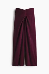 Pantalón de tiro alto color bordó, con corte holgado, piernas rectas y detalle drapeado con nudo girado en la parte frontal.