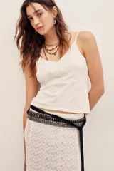 Top de punto de algodón color blanco, con tirantes finos y detalle de encaje bordado en el escote.