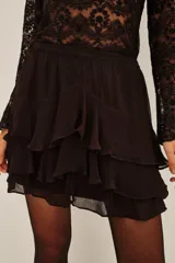 Falda corta negra con diseño de volados superpuestos, confeccionada en viscosa con forro de poliéster.