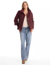 Tapado de tejido bouclé color marrón, con silueta evasé y largo a la cadera. Presenta cuello alto envolvente, cierre frontal oculto con botones a presión y bolsillos frontales de gran tamaño. Sus mangas son 3/4 con corte amplio y puños de tejido rib al tono que se extienden para cubrir las muñecas.