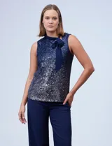 Blusa azul de microtul bordado con lentejuelas, marca Cable & Gauge. Cuello alto en gasa, escote asimétrico y lazo de ajuste.