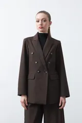 Blazer sastrero negro de doble botonadura con botones marrones, cuello solapa y mangas tres cuartos. Tiene dos bolsillos delanteros con solapa.