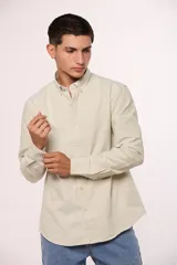 Camisa de manga larga en color gris, confeccionada en algodón, con cuello abotonado y cierre frontal de botones.