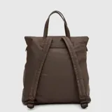 Mochila convertible en tote bag de diseño minimalista, color verde oscuro con acabado impermeable. Cuenta con asas superiores y detalles en cuero sintético gris, cierre superior y un llavero decorativo con la letra B en color turquesa.