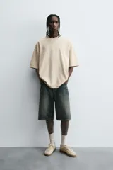 Camiseta color caqui de corte holgado, con cuello redondo y mangas cortas. Acabado con efecto lavado y ruedo irregular.