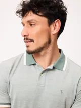 Remera polo de piqué de algodón melange color celeste, con cuello y puños en contraste blanco y azul, cierre frontal con botones y bordado pequeño en el pecho.