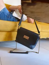 Bandolera negra de cuero con forro de tela, bolsillo interno, correa larga con cadena desmontable y correa corta de cuero desmontable.