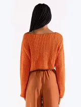 Sweater crop negro de punto abierto y manga larga con brillo sutil. Presenta escote bote y diseño relajado.
