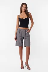 Short tipo bermuda recta de largo jort, color gris, tiro medio. Tiene cordón con punteras y tancas metálicas, cierre y botón. Incluye pasacintos, bolsillos laterales delanteros y dos bolsillos traseros. Detalle de llavero TW.