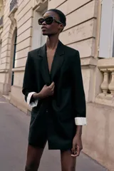 Blazer de lino color verde militar, con cuello solapa, hombreras y manga larga con puño revuelto con detalle a rayas. Cuenta con cierre frontal de un botón y bolsillos delanteros con solapa.