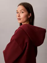 Campera canguro Calvin Klein de felpa color bordó, con capucha ajustable por cordones, cierre frontal completo de cremallera, mangas largas y bolsillos laterales. Presenta el logo monograma de la marca bordado en el pecho.