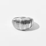 Anillo plateado con textura acanalada vertical.