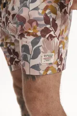 Short de baño con estampado floral en tonos rosados, marrones y grises, con cintura elástica y cordón ajustable blanco.