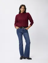 Sweater de tejido grueso con textura trenzada de ochos y cuello alto. Presenta mangas largas y un diseño clásico de punto abrigado.