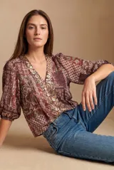 Blusa de manga corta abullonada, con escote en V y detalle de lentejuelas bordadas a lo largo de la abertura. Estampado estilo paisley en tonos borgoña y marrón.