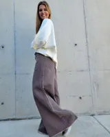 Pantalón de jean color beige, de corte recto y tiro alto, con ruedo deshilachado y cierre frontal con botón y cremallera.