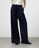 Pantalón de denim azul marino, tiro alto, con pinzas delanteras, canesú trasero y pierna ancha. Incluye cinturón de lazo del mismo tejido.