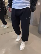 Pantalón de jogging negro de algodón premium, con cintura elástica, bolsillos laterales y puños elastizados en los tobillos. Presenta pequeño estampado tipográfico en la pierna izquierda.
