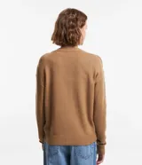 Cardigan corto de punto color marrón, con cuello en V, manga larga y cierre frontal con botones. Presenta puños y bajo acanalados.