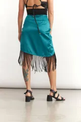 Minifalda cruzada color turquesa de seda con flecos negros en el borde.