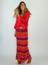 Pollera larga tejida a crochet con diseño de rayas horizontales en tonos naranja, fucsia y morado.