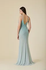 Vestido largo de tul color verde agua, con escote en V, tirantes dobles finos y detalles de pedrería brillante distribuida por toda la prenda. Presenta una silueta ajustada en el torso que se abre suavemente hacia el ruedo.