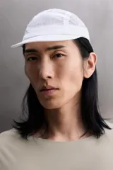 Gorra blanca confeccionada en tejido técnico ligero con estructura ripstop, resistente a desgarros. Cuenta con ajuste elástico en la parte posterior y estampado frontal de logo con relieve.