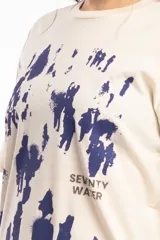 Remera de algodón color beige con estampado abstracto en azul marino y texto pequeño en el frente.