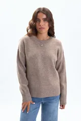 Buzo de tejido de punto en color beige, con cuello redondo a la base, mangas largas y puños y ruedo acanalados.