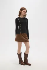 Remera de algodón de calce ajustado, con cuello redondo y manga larga. Presenta una hilera de botones decorativos dorados en el hombro y lateral derecho.