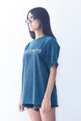 Remera de corte oversize con efecto de lavado ácido en color azul petróleo. Presenta un estampado gráfico frontal en color amarillo con tipografía moderna y la inscripción 'Montevideo, UY'.
