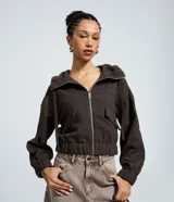 Campera tipo bomber color marrón oscuro, con capucha, cierre frontal de cremallera, bolsillos delanteros con solapa y puños elásticos.