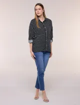 Camisa de rayón negra con patrón de líneas blancas. Presenta cuello camisero, cierre frontal con botones, mangas largas con puños vueltos y un diseño con corte horizontal que alterna líneas verticales en la parte superior y horizontales en la inferior.