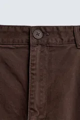Pantalón cargo de corte relajado confeccionado en tejido de algodón con efecto lavado. Presenta cintura con pliegues frontales, bolsillos laterales con solapa en las perneras, bolsillos frontales y bolsillos traseros con solapa. Cierre frontal con cremallera y botón.