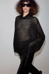 Camisa de hilatura con viscosa color negro, con cuello subido y manga larga ancha. Presenta aplicaciones de abalorios combinados a tono en toda la prenda y bajo recto.